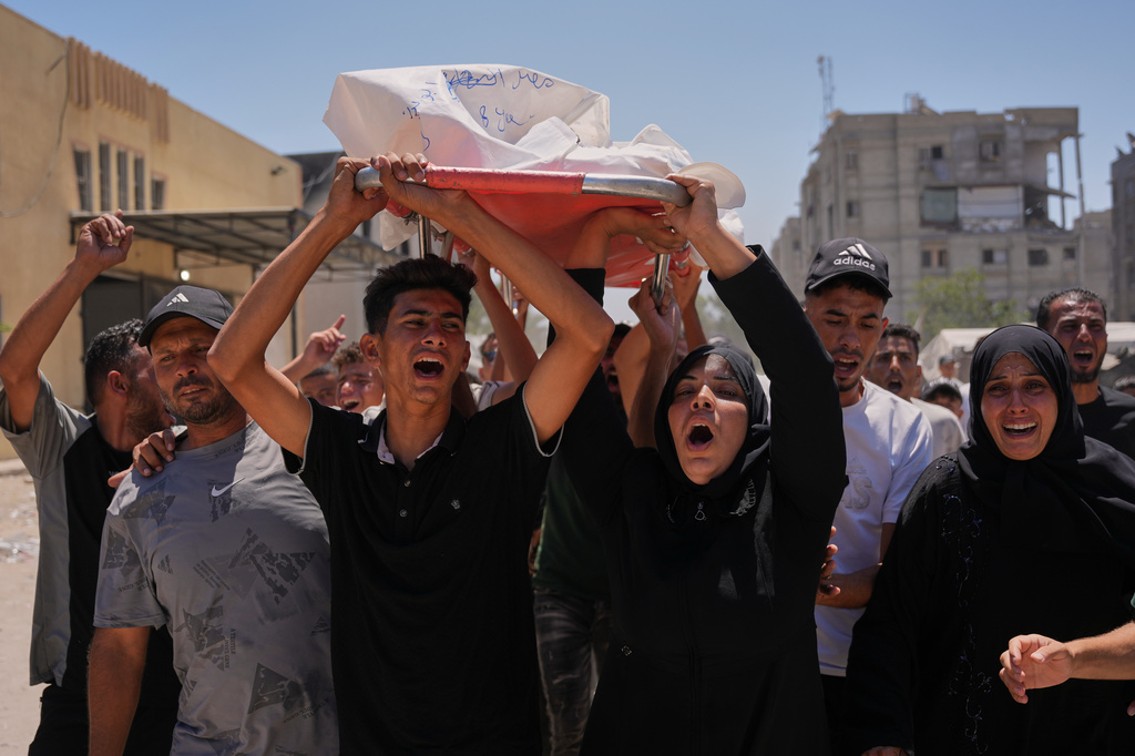 Warda Abu Shaar, center right, carries the body of her 10-year-old son, Motaz Abu Shaar, who was killed by Israeli fire, during his funeral outside Nasser Hospital in Khan Younis, southern Gaza Strip, Tuesday, July 14, 2026. (AP Photo/Abdel Kareem Hana)