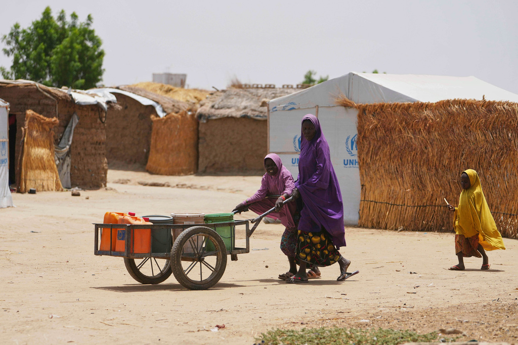 FILE - A woman and young girl displaced from Boko Haram attacks push a cart in Dikwa, Borno province, north east Nigeria, Tuesday, April 29, 2025. (AP Photo/Sunday Alamba, File)