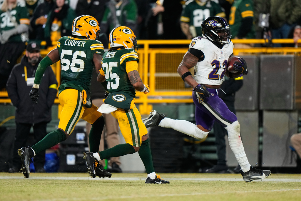 Baltimore Ravens running back Derrick Henry (22) runs the ball toward the end zone to score a touchdown past Green Bay Packers linebacker Edgerrin Cooper (56) and cornerback Keisean Nixon (25) during the second half of an NFL football game, Saturday, Dec. 27, 2025, in Green Bay, Wis. (AP Photo/Morry Gash)