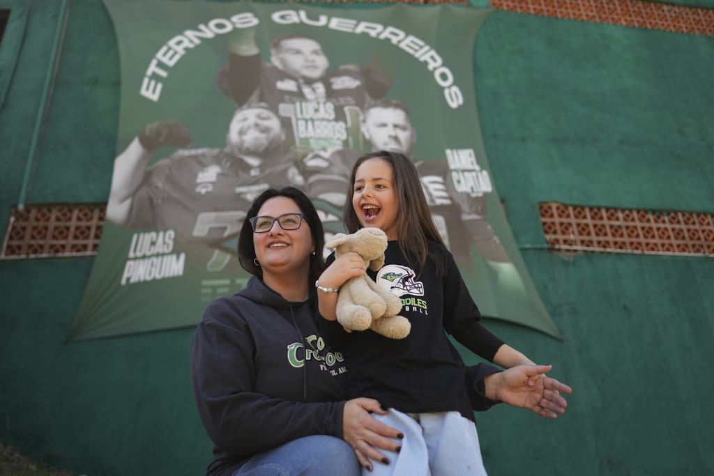 Elisa Richter — the widow of Coritiba Crocodiles' Daniel Capitao, one of the three athletes who died in a 2024 team bus crash — and daughter Helena pose for a photo before a football game against the Brown Spiders in Curitiba, Brazil, Sunday, Aug. 17, 2025. (AP Photo/Andre Penner)
