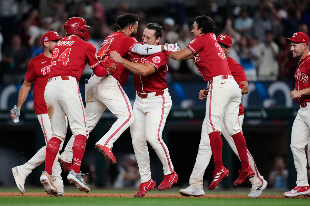 Texas Rangers' Brandon Nimmo (24), Ezequiel Duran, second from left, Wyatt Langford, Nicky Lopez, right front, and the rest of the team celebrate Duran's run-scoring single in the 10th inning of a baseball game against the Los Angeles Angels Friday, Aug. 21, 2026, in Arlington, Texas. (AP Photo/Tony Gutierrez)