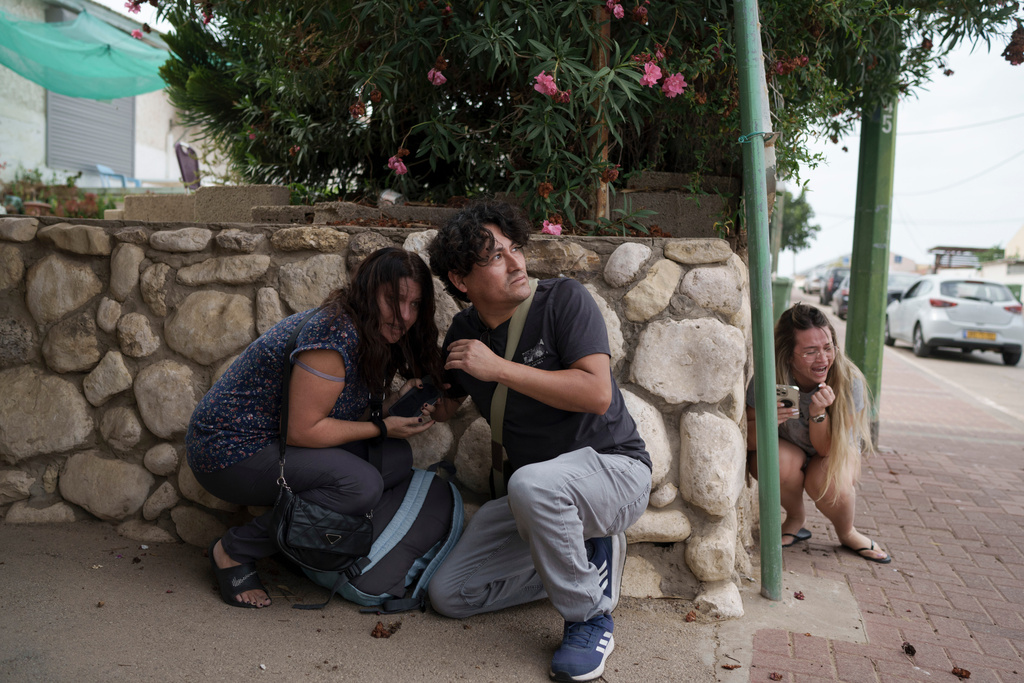 People take cover from incoming rocket fire from the Gaza Strip in Ashkelon, southern Israel, Wednesday, Oct. 11, 2023. (AP Photo/Leo Correa)