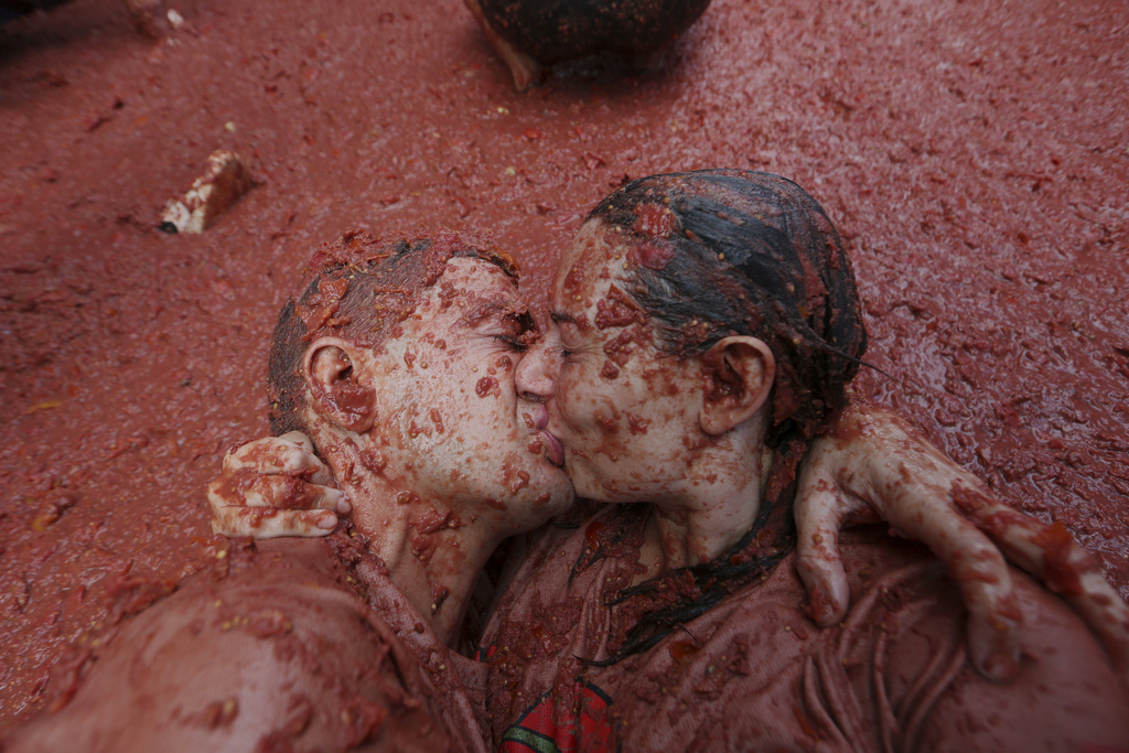 A couple kiss in a puddle of tomatoes during the annual "Tomatina" tomato fight fiesta, in the village of Bunol near Valencia, Spain, Wednesday, Aug. 27, 2025. (AP Photo/Alberto Saiz)