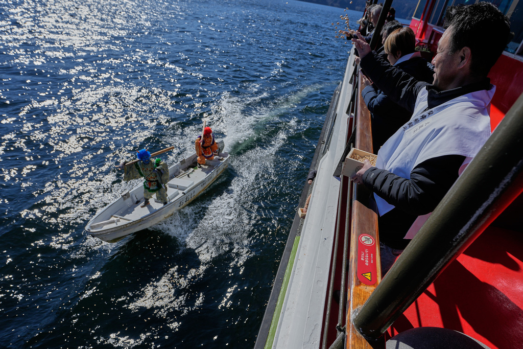 Participants thrown lucky beans to students dressed as 'Oni', or demon-like figures in Japanese folklore, during the annual Bean Throwing Festival, at Lake Ashi in Hakone, Japan, Tuesday, Feb. 3, 2026. (AP Photo/Eugene Hoshiko)