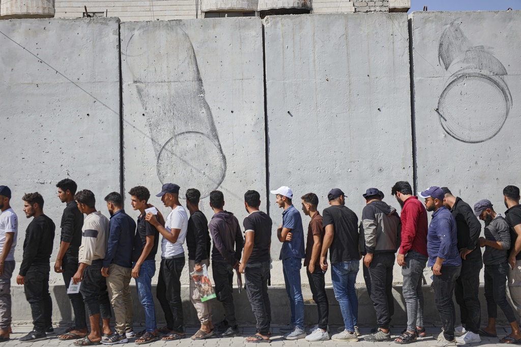 Young Kurdish men line up to sign up to join Syrian government's General Security forces at a police station in Afrin, Syria, an area in the country's north from which Kurds were forcibly displaced years ago, Thursday Aug. 21, 2025. (AP Photo/Omar Albam)