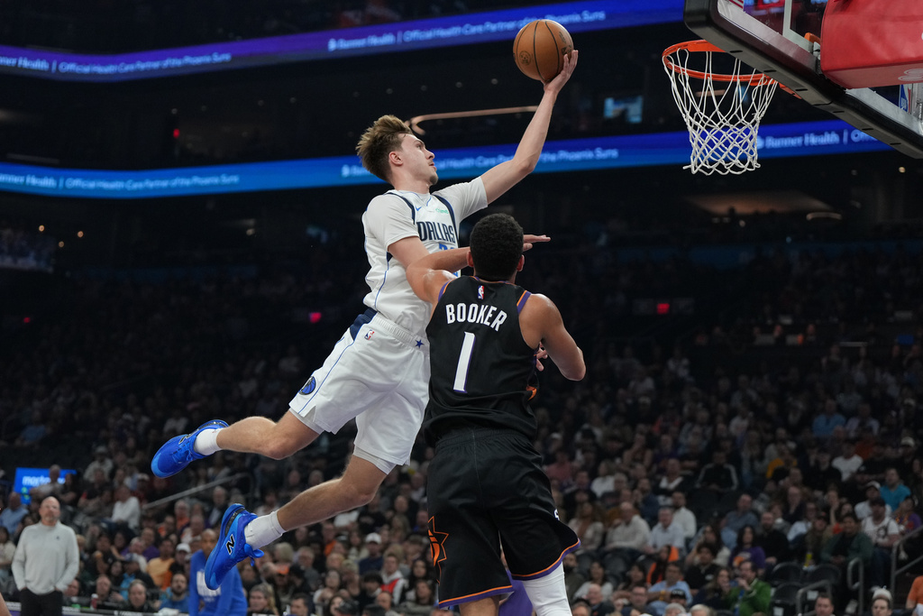 Dallas Mavericks forward Cooper Flagg shoots over Phoenix Suns guard Devin Booker (1) during the first half of an NBA basketball game, Tuesday, Feb. 10, 2026, in Phoenix. (AP Photo/Rick Scuteri)