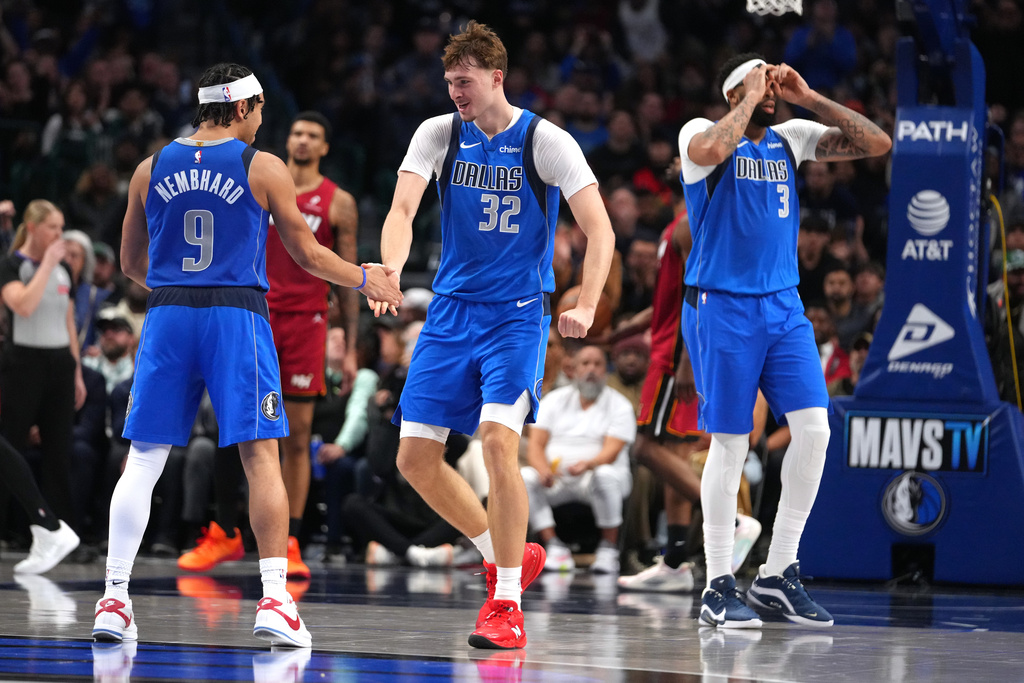 Dallas Mavericks guard Ryan Nembhard (9), forward Cooper Flagg (32) and forward Anthony Davis (3) react after a basket against the Miami Heat during the second half of an NBA basketball game Wednesday, Dec. 3, 2025, in Dallas. (AP Photo/Julio Cortez)