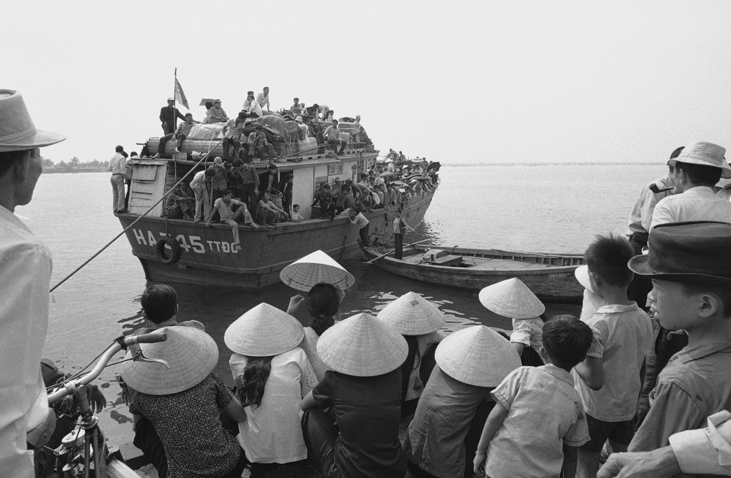 FILE - South Vietnamese refugees, foreground, who arrived on Friday, March 28, 1975 at the port city of Da Nang, South Vietnam, watch hopefully, as a boat loaded with refugees approaches the dock. The helter Skelter flight from advancing North Vietnamese resulted in the separation of navy families. Refugees already in the city Jam docks looking for their relatives to arrive. (AP Photo, File)