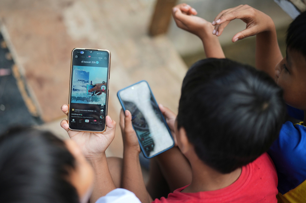 Boys use their mobile phone in Jakarta, Indonesia, Wednesday, April 29, 2026. (AP Photo/Achmad Ibrahim)