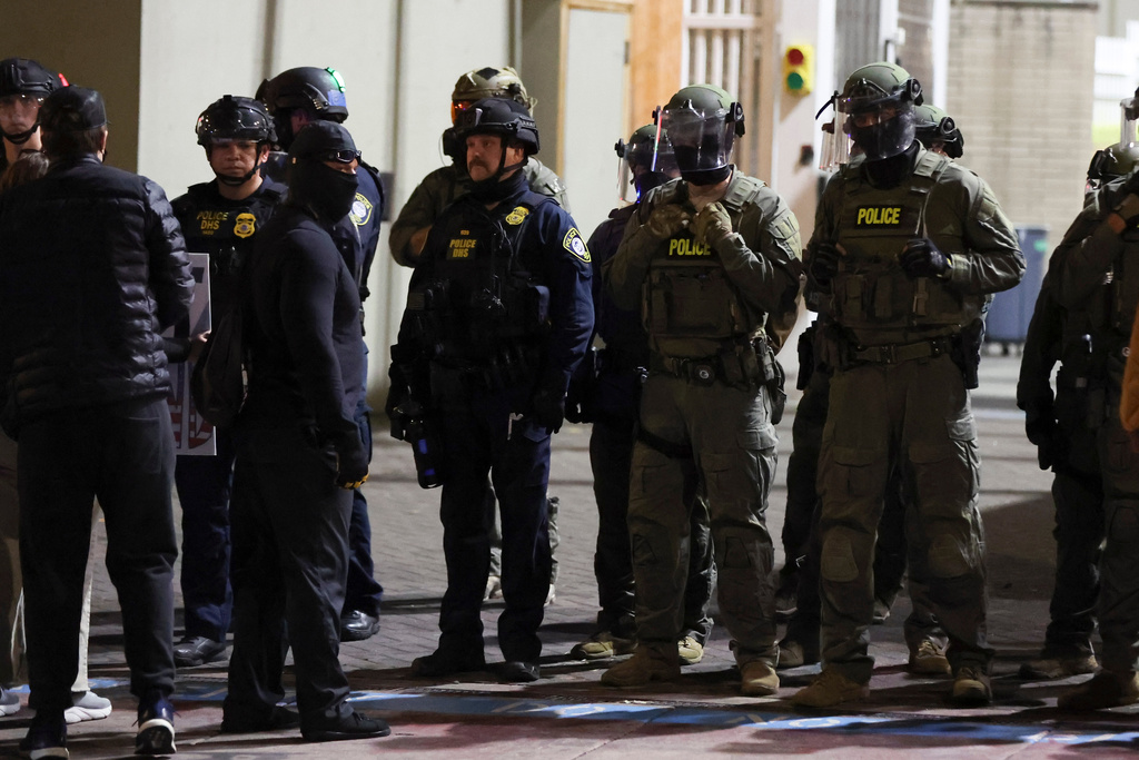 Federal agents line a driveway as people protest outside a U.S. Immigration and Customs Enforcement facility in Portland, Oregon, Friday, Oct. 3, 2025. (AP Photo/Amanda Loman)
