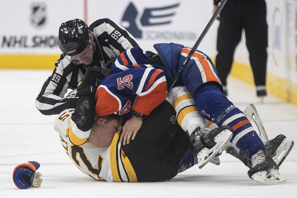 Boston Bruins' Sean Kuraly (52) and Edmonton Oilers' Darnell Nurse (25) fight during the third period of an NHL hockey game in Edmonton, Alberta, on Wednesday, Dec. 31, 2025. (Jason Franson/The Canadian Press via AP)