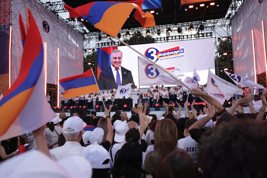 Supporters of Russian-Armenian tycoon Samvel Karapetyan, on screen, attend a rally with Armenian national flags against incumbent Prime Minister Nikol Pashinyan at Republic Square in Yerevan, Armenia, Wednesday, June 3, 2026, as Karapetyan, who heads the Strong Armenia party, has faced criminal charges that he rejected as politically driven and campaigned from under house arrest. (AP Photo/Anthony Pizzoferrato)