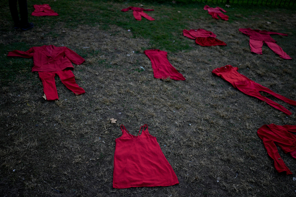 FILE - Outfits representing women who were disappeared or murdered lie on the grass outside Congress during a march marking the ninth anniversary of the "Ni Una Menos" (Not One Fewer) women's movement in Buenos Aires, Argentina, June 3, 2024. (AP Photo/Natacha Pisarenko, File)