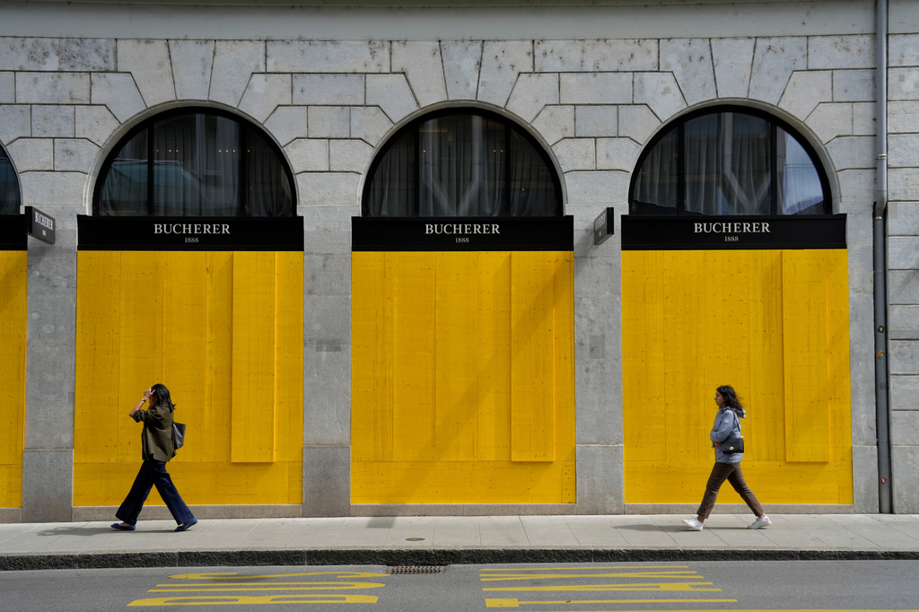 Pedestrians walk past the boarded-up windows of a shop, ahead of expected protests for the G7 summit, in Geneva, Switzerland, Tuesday, June 9, 2026. (AP Photo/Baz Ratner)