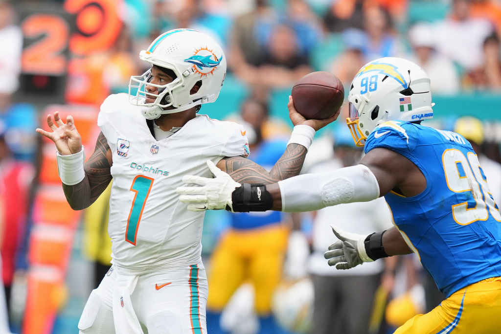 Miami Dolphins quarterback Tua Tagovailoa throws a pass under pressure from Los Angeles Chargers linebacker Odafe Oweh during the first half of an NFL football game Oct. 12, 2025, in Miami Gardens, Fla. (AP Photo/Rebecca Blackwell)