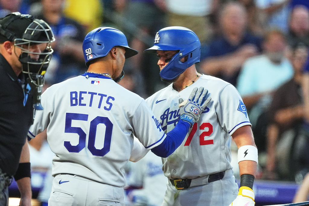 Los Angeles Dodgers' Miguel Rojas, right, congratulates Mookie Betts as he crosses home plate after hitting a solo home run off Colorado Rockies starting pitcher Kyle Freeland in the fourth inning of a baseball game Wednesday, Aug. 19, 2026, in Denver. (AP Photo/David Zalubowski)