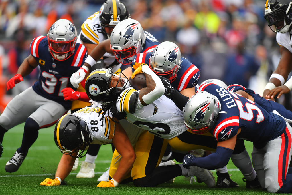 Pittsburgh Steelers' Rico Dowdle (13) drives past New England Patriots' Christian Elliss (53) during the first half of an NFL football game, Sunday, Sept. 20, 2026, in Foxboro, Mass. (AP Photo/Steven Senne)