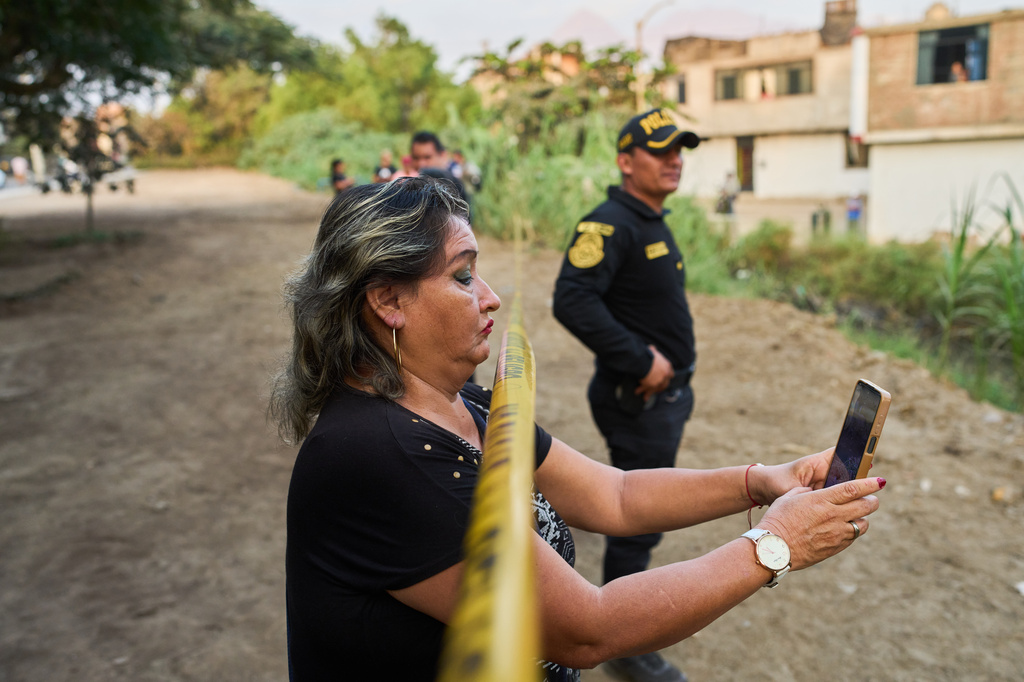 A neighbor records the scene with a cellphone as police recover the body of Jose Perez from a ravine where he was found shot in Trujillo, Peru, Friday, May 30, 2026. (AP Photo/Rodrigo Abd)