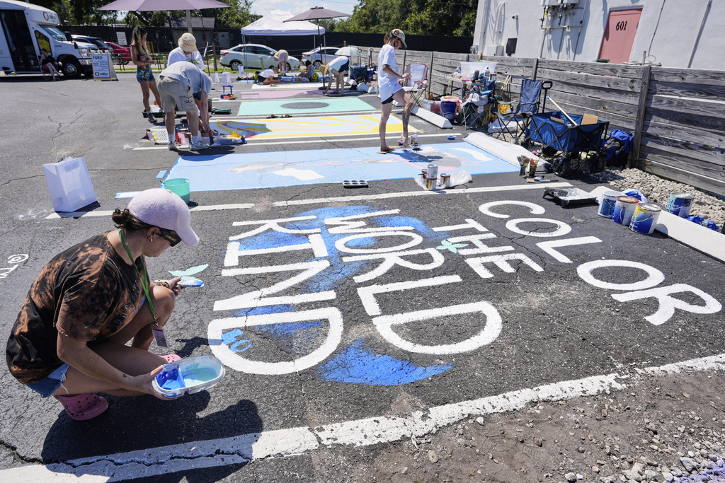 Tyler Blum paints a parking space at a local restaurant to support the LBGTQ+ community and to protest state mandates on crosswalk art Monday, Sept. 15, 2025, in Orlando, Fla. (AP Photo/John Raoux)