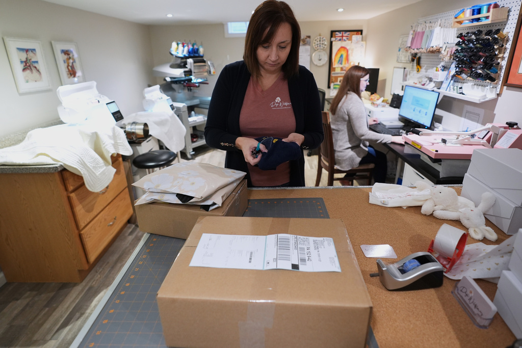 Fran Poirier, left, and her sister, Sue Bacarro, right, fill orders at their Etsy shop, Digi Wildflowers, Thursday, Oct. 30, 2025, in Windsor, Ontario, Canada. (AP Photo/Paul Sancya)