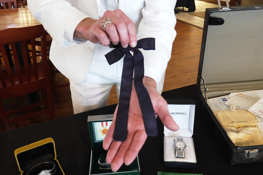Auctioneer Jonathan Klunk shows a black bow tie worn by KFC founder Harland Sanders, Wednesday, July 22, 2026, in Shelbyville, Ky. (AP Photo/Dylan Lovan)