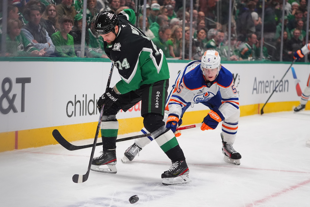 Dallas Stars left wing Jamie Benn (14) and Edmonton Oilers defenseman Connor Murphy, right skate for the puck during the first period of an NHL hockey game, Thursday, March 12, 2026, in Dallas. (AP Photo/LM Otero)