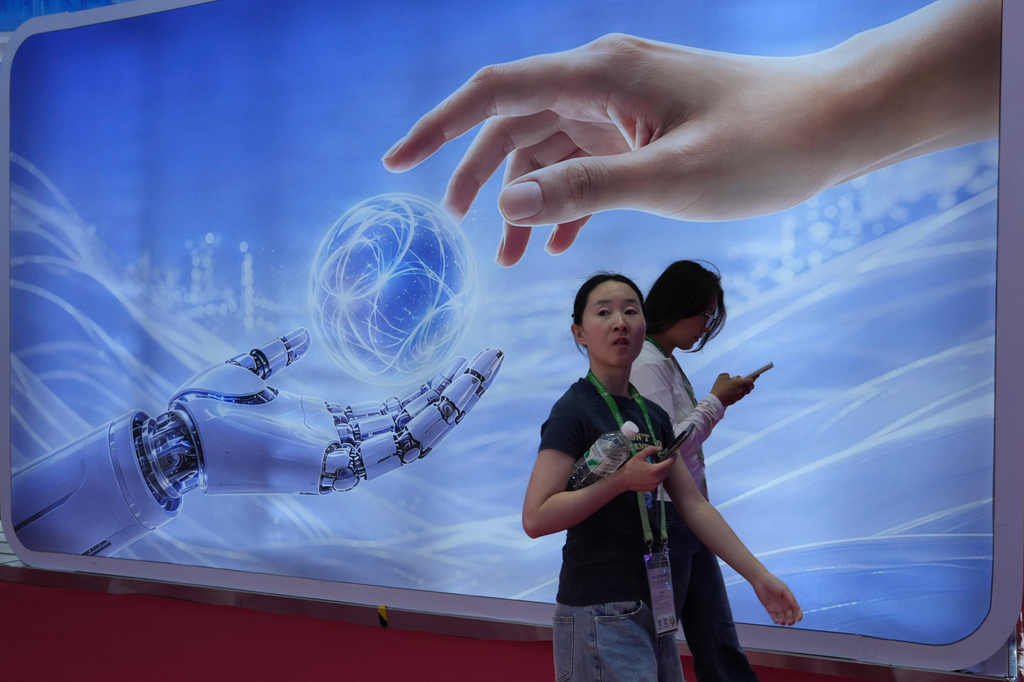 Visitors walk past a display depicting artificial intelligence and a human hand at the China International Supply Chain Expo in Beijing on Monday, June 22, 2026. (AP Photo/Ng Han Guan)