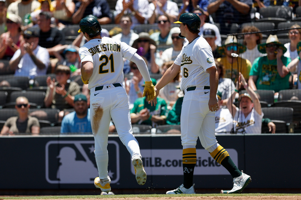 Athletics' Tyler Soderstrom (21) is greeted by designated hitter Nick Kurt, right after they scored on a single hit by Carlos Cortes during the first inning of a baseball game against the Colorado Rockies, Sunday, June 14, 2026, in Las Vegas. (AP Photo/Caroline Brehman)