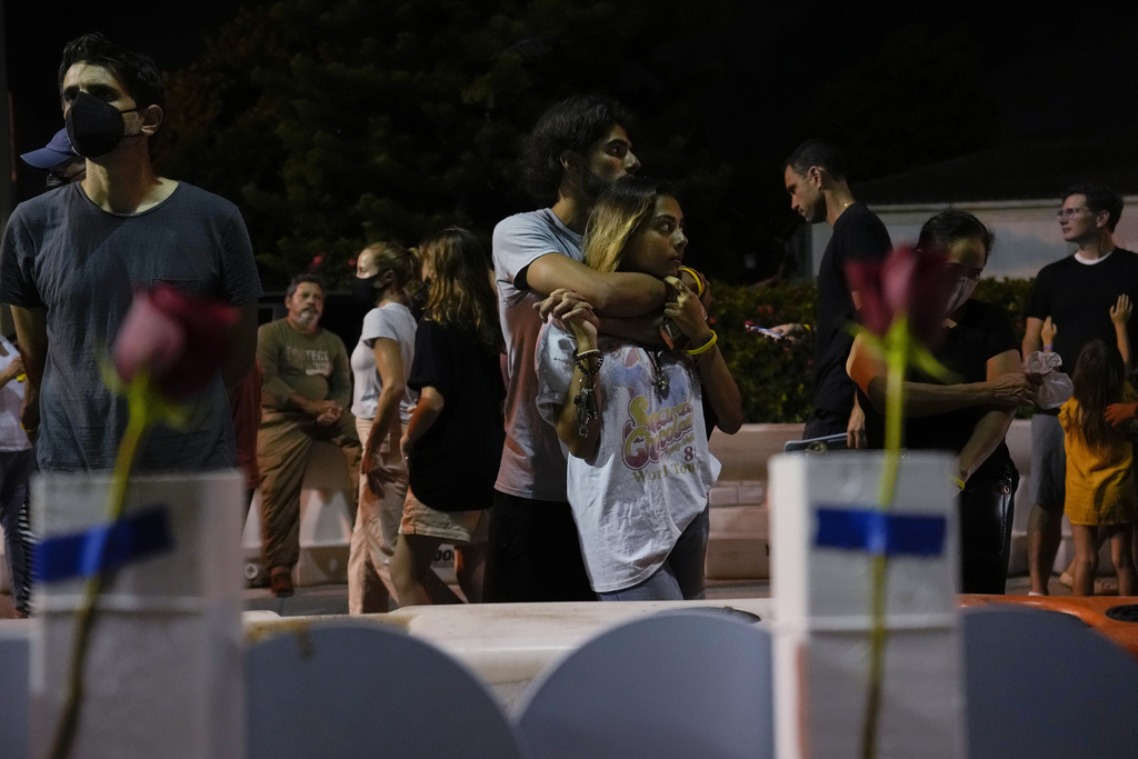 FILE - Well-wishers and mourners gather at a makeshift memorial for the victims of the Champlain Towers South condo building collapse, for a multi-faith vigil near the site where the building once stood in Surfside, Fla, July 15, 2021. (AP Photo/Rebecca Blackwell)