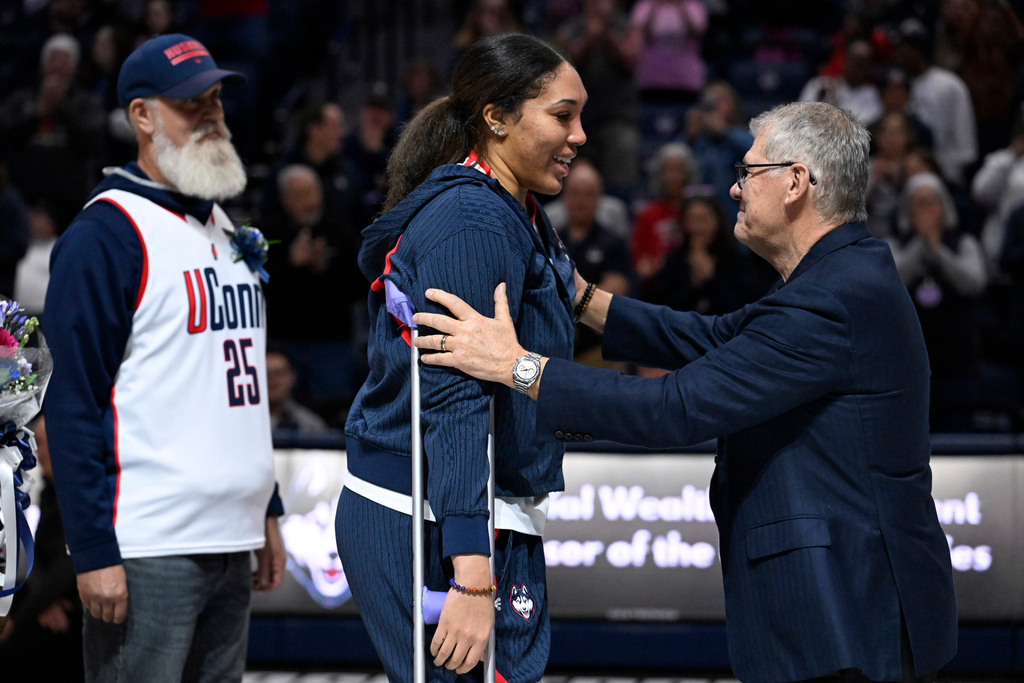 UConn head coach Geno Auriemma, right, reaches for UConn forward Ice Brady, center, as she is honored in a Senior Day ceremony after an NCAA college basketball game against Providence, Sunday, Feb. 22, 2026, in Storrs, Conn. (AP Photo/Jessica Hill)