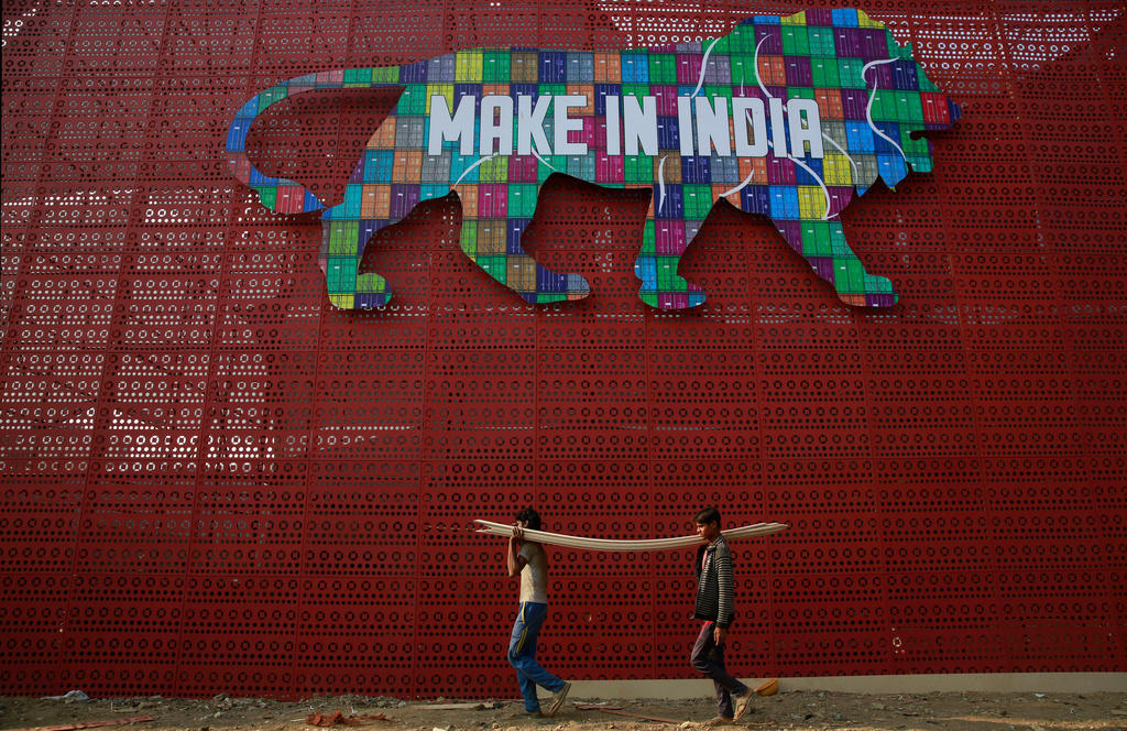 FILE - Laborers carry narrow planks of wood to be used for building a pavilion for the Make In India summit in Mumbai, India, Feb. 9, 2016. (AP Photo/Rafiq Maqbool, File)