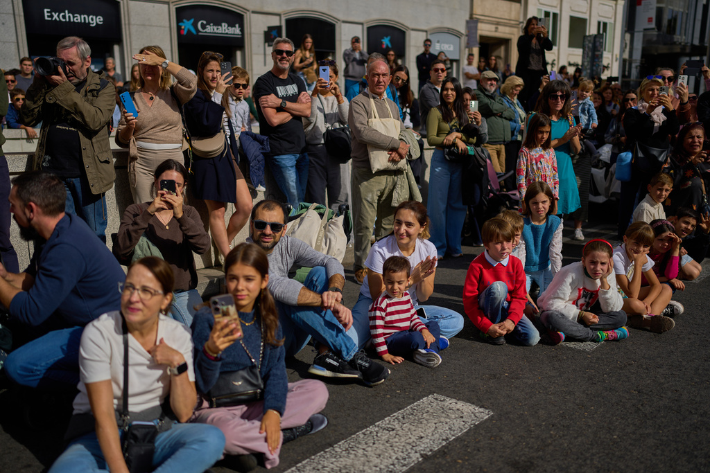 People watch as sheep are guided through central Madrid, Spain, moving through the streets in defense of ancient grazing and migration rights, Sunday, Oct. 19, 2025. (AP Photo/Manu Fernandez)