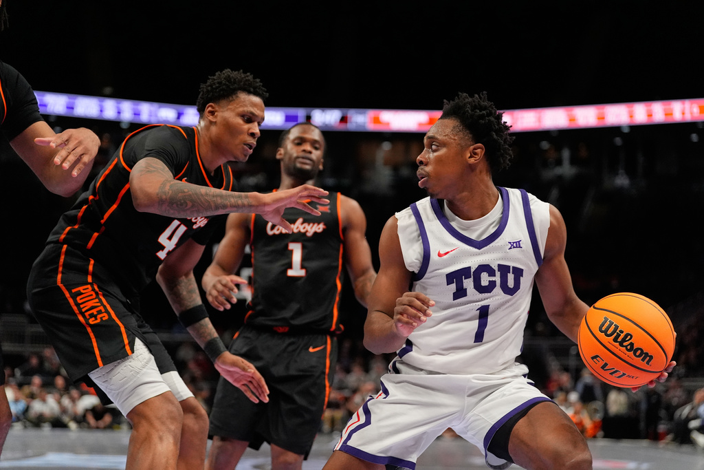 TCU's Jayden Pierre, right, eludes Oklahoma State's Christian Coleman (4) and Kanye Clary, center, during the second half of an NCAA college basketball game in the second round of the Big 12 Conference tournament Wednesday, March 11, 2026, in Kansas City, Mo. (AP Photo/Charlie Riedel)