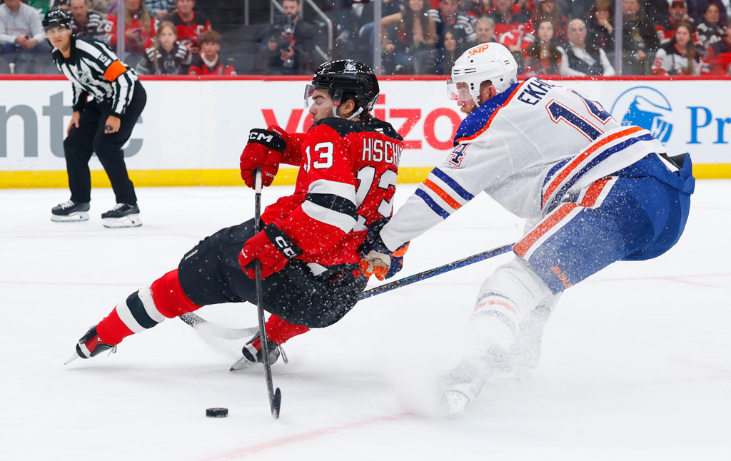 CORRECTS YEAR TO 2025, NOT 2024 - New Jersey Devils center Nico Hischier (13) battles Edmonton Oilers defenseman Mattias Ekholm (14) for the puck during the second period of an NHL hockey game, Saturday, Oct. 18, 2025, in Newark, N.J. (AP Photo/Noah K. Murray)