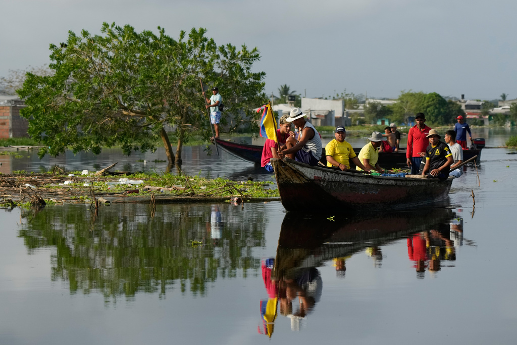 Residents ride in a boat through a flooded area in Monteria, Colombia, Tuesday, Feb. 10, 2026. (AP Photo/Fernando Vergara)