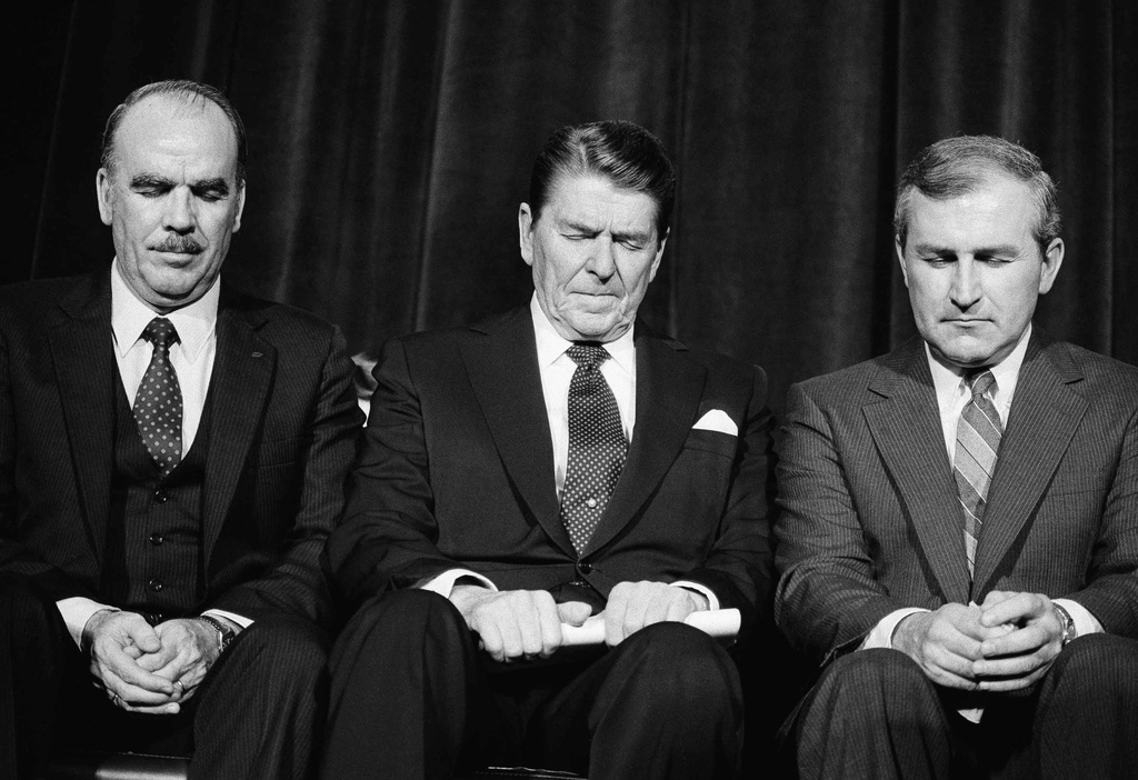 FILE - President Ronald Reagan prays with National Association of Evangelicals President Arthur Gay, left, following his address to the organization's convention asking for help in winning approval of a constitutional amendment permitting prayer in school in Columbus, Ohio, March 7, 1984. (AP Photo/Barry Thumma, File)