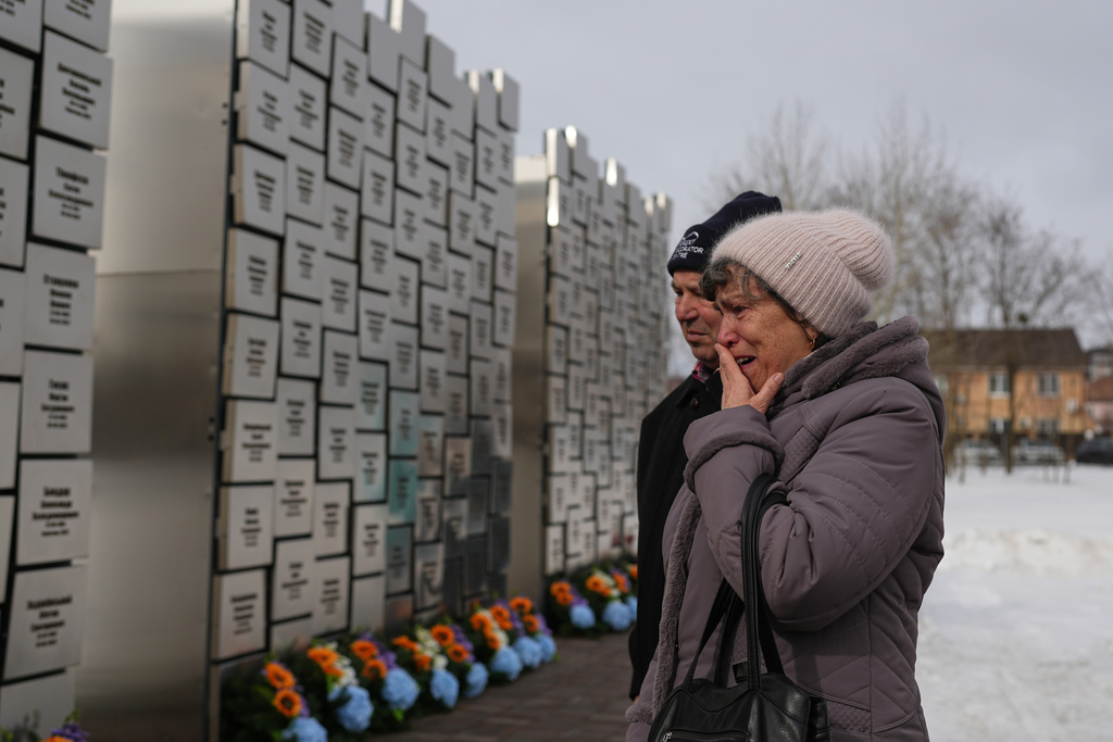 Relatives of those killed during the Russian occupation react at the Wall of Remembrance during a ceremony to mark the fourth anniversary of the Russian invasion of Ukraine, in Bucha, Ukraine, Tuesday, Feb. 24, 2026. (AP Photo/Sergei Grits)
