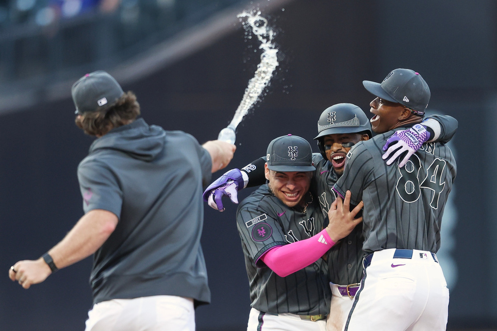 New York Mets' Francisco Lindor, center, celebrates his game winning base hit with pitcher Jefry Yan (84) and Francisco Alvarez, left, during the ninth inning of a baseball game against the Washington Nationals, Saturday, Aug. 15, 2026, in New York. (AP Photo/Heather Khalifa)