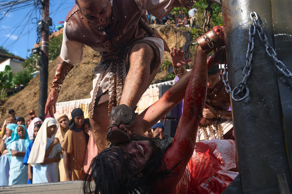 A devotee dressed as a Roman soldier places his foot on the face of a penitent depicting the role of Jesus Christ during a Way of the Cross reenactment as part of Holy Week celebrations in the Petare neighborhood in Caracas, Venezuela, Good Friday, April 3, 2026. (AP Photo/Ariana Cubillos)