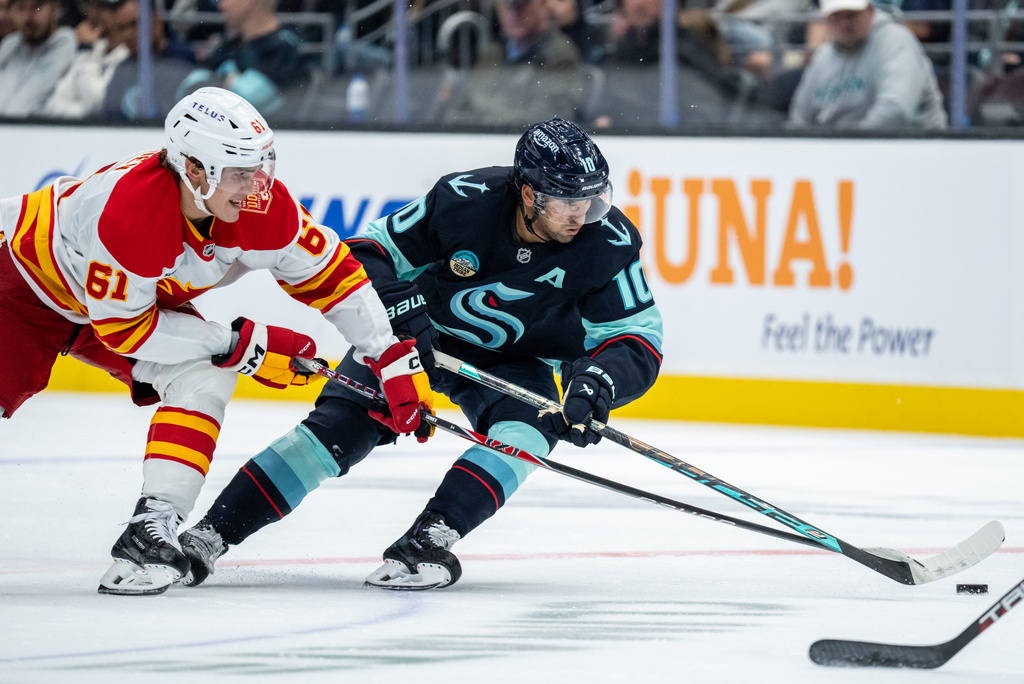 Seattle Kraken forward Matty Beniers, right, skates against Calgary Flames forward Aydar Suniev during the second period of a preseason NHL hockey game, Thursday, Sept. 24, 2026, in Seattle. (AP Photo/Stephen Brashear)