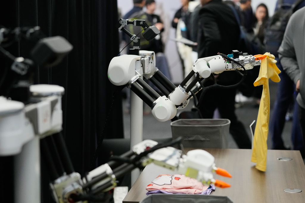 Robots, made by Weave Robotics, fold clothes inside the exhibition room at the Humanoids Summit, Thursday, Dec. 11, 2025, in Mountain View, Calif. (AP Photo/Godofredo A. Vásquez)