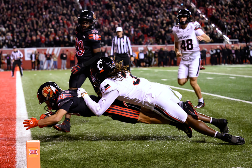 Utah wide receiver Mana Carvalho (28) dives into the end zone to score a touchdown on a punt return tackled by Cincinnati defensive back Kye Stokes (3) during the second half an NCAA college football game, Saturday, Nov. 1, 2025, in Salt Lake City, Utah. (AP Photo/Tyler Tate)