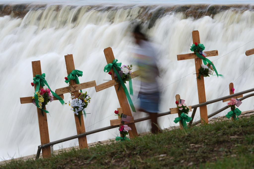 A young girl runs past crosses at a make-shift memorial honoring flood victims, July 13, 2025, in Kerrville, Texas. (AP Photo/Eric Gay, File)
