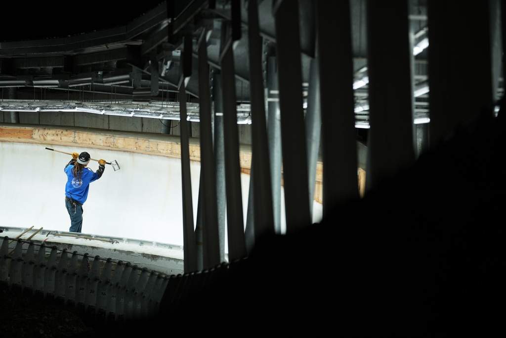 A man works on the track ahead of a three-day skeleton and bobsled World Cup stage and Olympic test event in Cortina D'Ampezzo, Italy, Wednesday, Nov. 19, 2025. (AP Photo/Andrew Medichini)