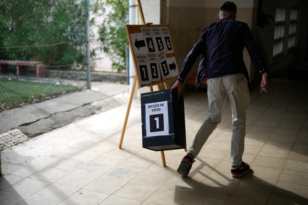 A worker picks up an empty ballot box at a polling station for Portugal's municipal elections in Lisbon, Sunday, Oct. 12, 2025. (AP Photo/Armando Franca)