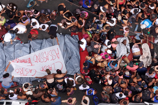 Residents gather around the bodies of men killed in a police raid targeting the Comando Vermelho gang the day before, next to a banner reading "Claudio Castro Murderer," referring to Rio de Janeiro state Governor Claudio Castro, in the Complexo da Penha favela of Rio de Janeiro, Brazil, Wednesday, Oct. 29, 2025. (AP Photo/Silvia Izquierdo) Residents gather around the bodies of men killed in a police raid targeting the Comando Vermelho gang the day before, next to a banner reading "Claudio Castro Murderer," referring to Rio de Janeiro state Governor Claudio Castro, in the Complexo da Penha favela of Rio de Janeiro, Brazil, Wednesday, Oct. 29, 2025. (AP Photo/Silvia Izquierdo)