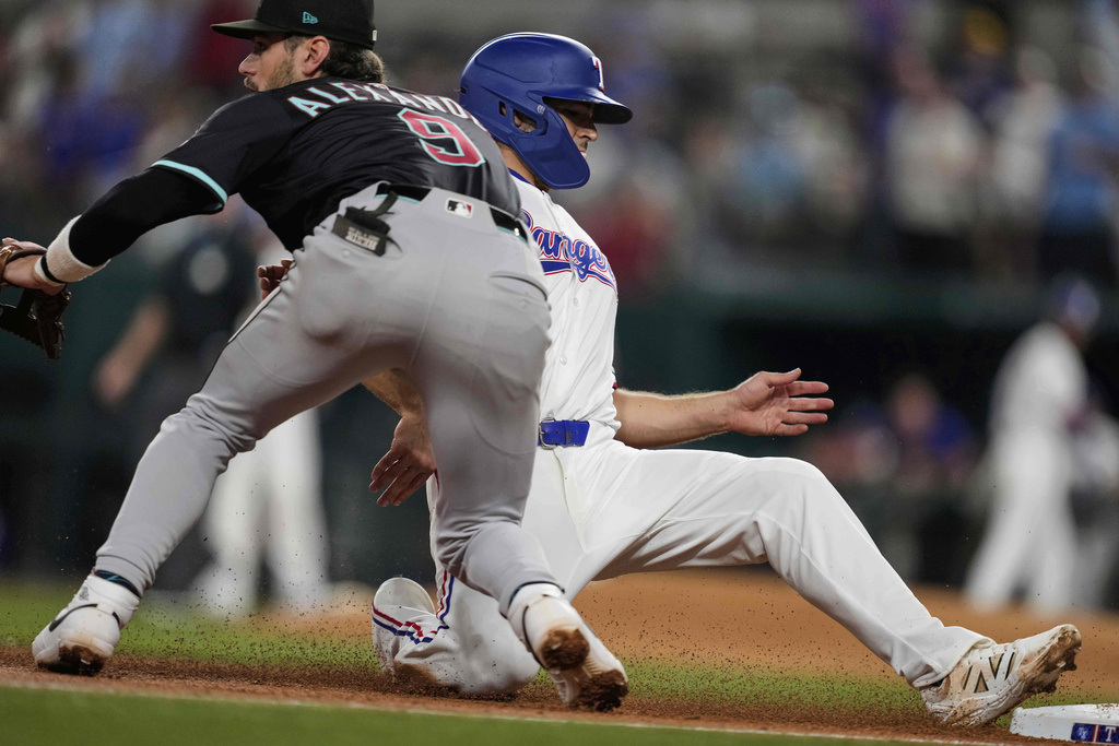 Texas Rangers' Josh Smith advances to third on a sacrifice fly by Marcus Semien as Arizona Diamondbacks third baseman Blaze Alexander waits on the throw to the bag in the third inning of a baseball game Tuesday, Aug. 12, 2025, in Arlington, Texas. (AP Photo/Tony Gutierrez)
