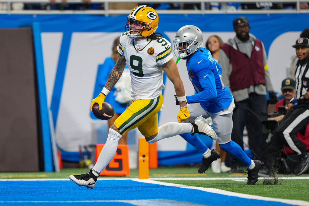 Green Bay Packers wide receiver Christian Watson (9) runs in for a touchdown on front of Detroit Lions cornerback Amik Robertson (21) during the second half an NFL football game in Detroit, Thursday, Nov. 27, 2025. (AP Photo/Ryan Sun)