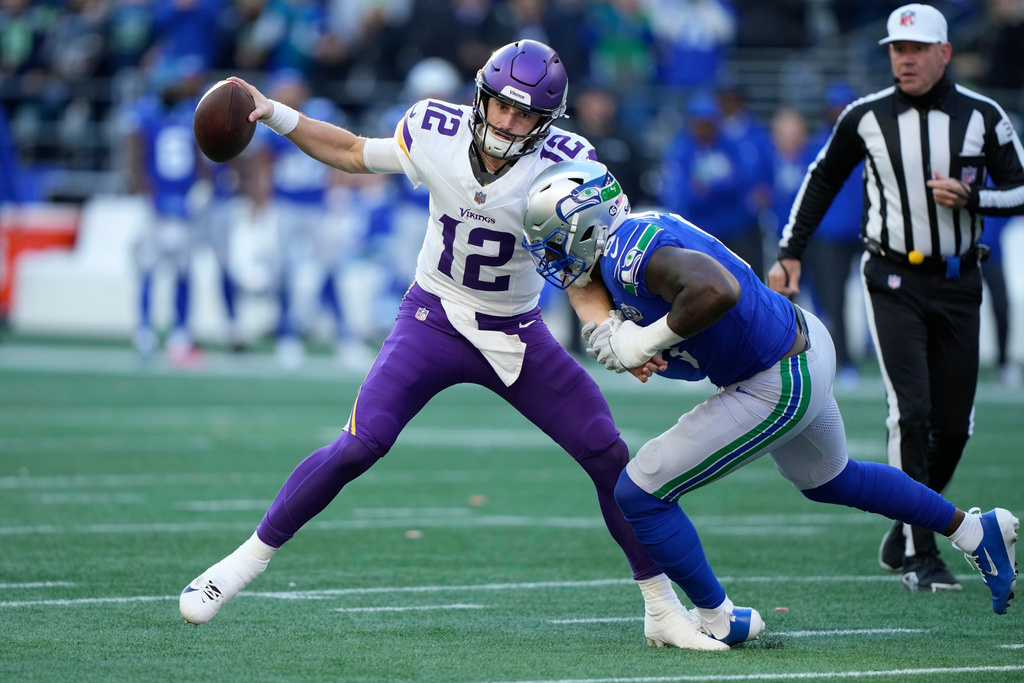 Minnesota Vikings quarterback Max Brosmer (12) passes an interception against Seattle Seahawks defensive end DeMarcus Lawrence (0) during the first half of an NFL football game Sunday, Nov. 30, 2025, in Seattle. (AP Photo/Stephen Brashear)