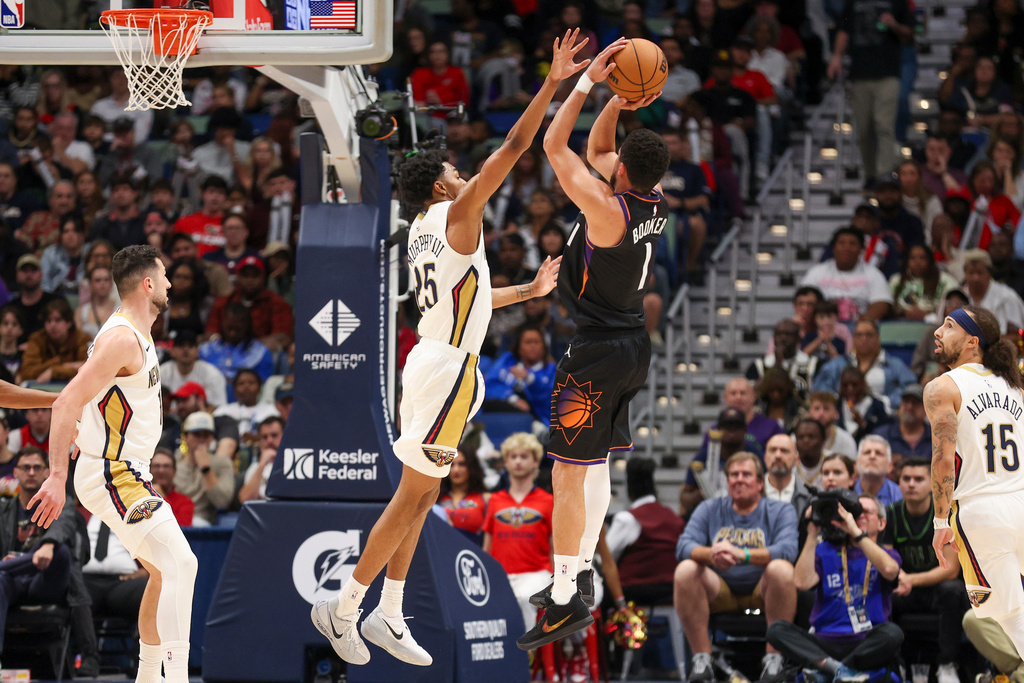 Phoenix Suns guard Devin Booker (1) shoots a jumper over New Orleans Pelicans forward Trey Murphy III, center left, in the first half of an NBA basketball game Friday, Dec. 26, 2025, in New Orleans. (AP Photo/Peter Forest)